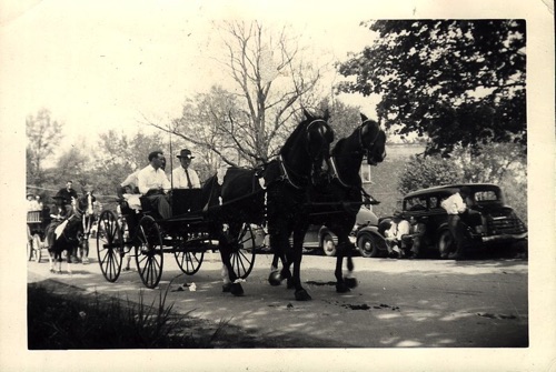Open carriage with two men, a woman and baby in front of the Corporation Building in 100th Hambletonian Anniversary Parade, May 5, 1949. chs-003441